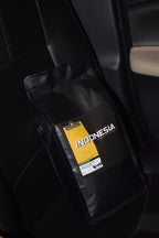 Black coffee bag of roasted coffee beans with 'Indonesia single origin' label on a car seat from Roastomatic