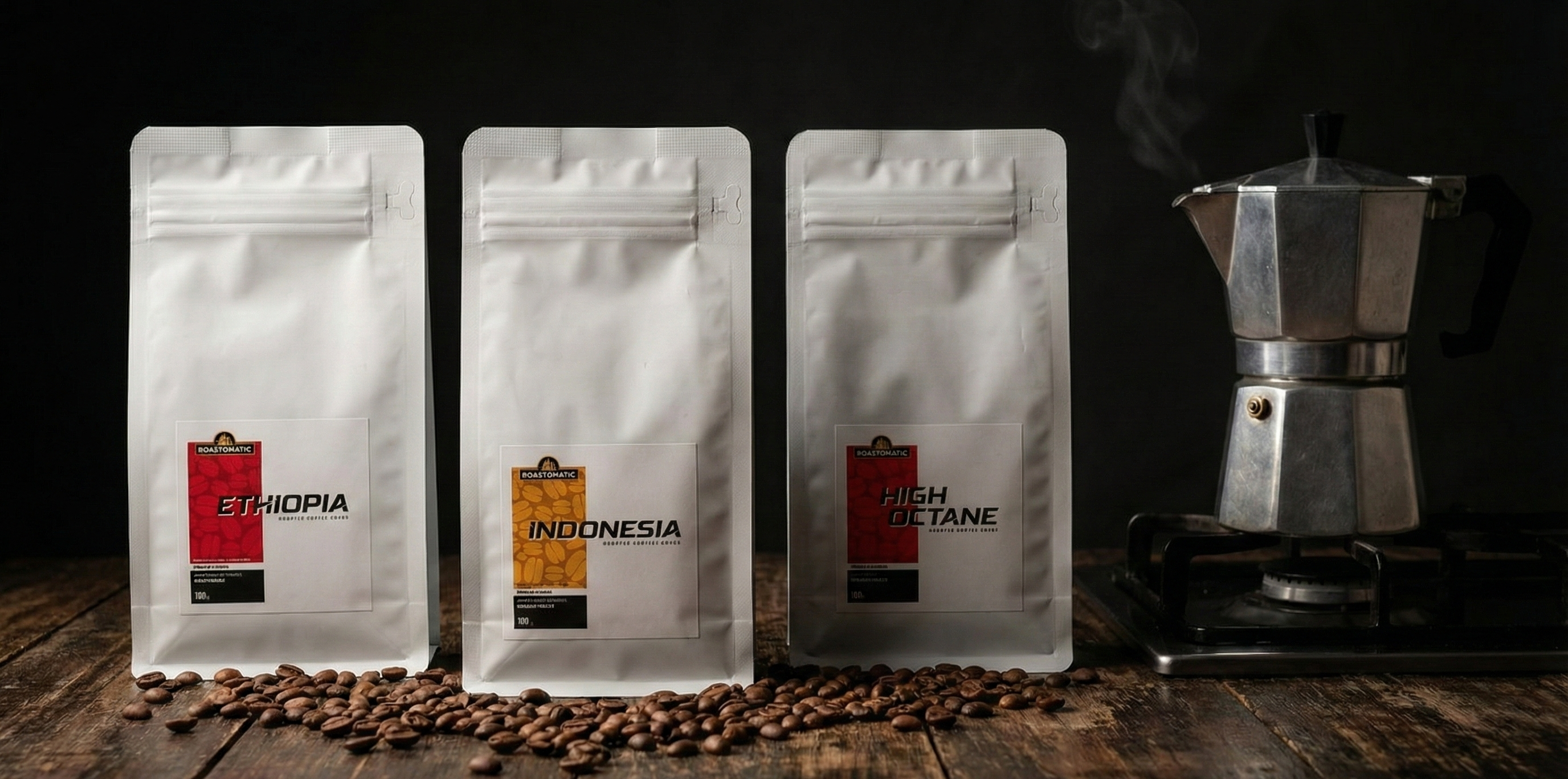 Roastomatic three coffee bags labeled Ethiopia, Indonesia, and High Octane with a mokapot on a wooden surface.